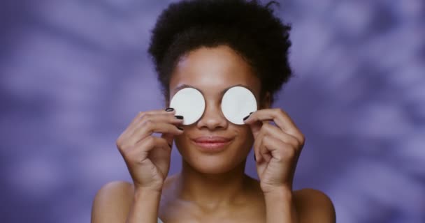 Modelo afro-americano removendo as almofadas de algodão com as quais ela cobriu os olhos — Vídeo de Stock