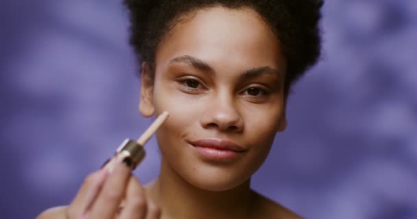 Africký americký model nanáší tonáž krém na její obličej a usmívá — Stock video