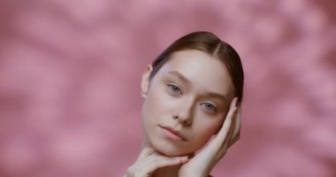 Doğal güzellikte beyaz bir model, elleriyle yüzüne dokunuyor.