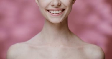 Boynu ve yakası çıplak genç bir kadın geniş gülümsüyor.