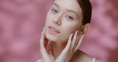 Doğal güzellikte beyaz bir model, elleriyle yüzüne dokunuyor.