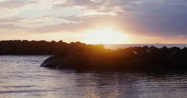 Um grupo de rochas vulcânicas localizadas perto da costa nas ondulações das ondas do mar — Vídeo de Stock