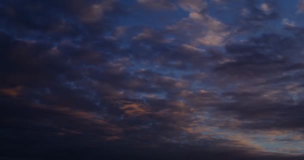 El cielo cubierto de nubes oscuras con reflejos rosados del sol poniente — Vídeo de stock