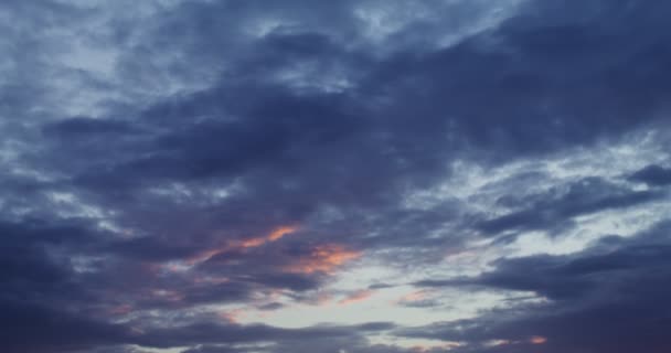 Der Himmel ist mit dicken Wolken bedeckt, die vom hellen Licht der aufgehenden Sonne erhellt werden — Stockvideo