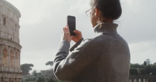 Una giovane donna fotografa il Colosseo su un cellulare — Video Stock