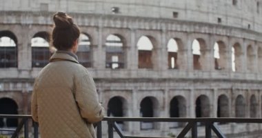Genç bir kadın Colosseum 'un yakınındaki bir gözlem güvertesinde fotoğraf çekiyor.