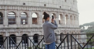 Kolezyum yakınlarındaki bir cep telefonuyla Roma 'nın fotoğraflarını çeken bir kadın.