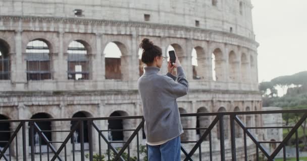 Egy nő fényképeket készít Rómáról egy mobiltelefonon a Kolosszeum közelében. — Stock videók