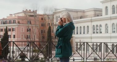 Bir kadın kamerayla fotoğraf çekiyor, gözlem güvertesinde duruyor.