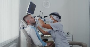 Bir otorhinolingolog tıbbi ayna kullanarak bir hastanın sinüslerini inceler.