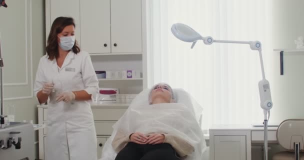 Косметолог делает укол лица пациента с помощью медицинских препаратов — стоковое видео