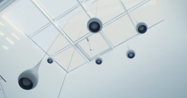 Zahlreiche weiße Kronleuchter hängen von der gläsernen Decke — Stockvideo
