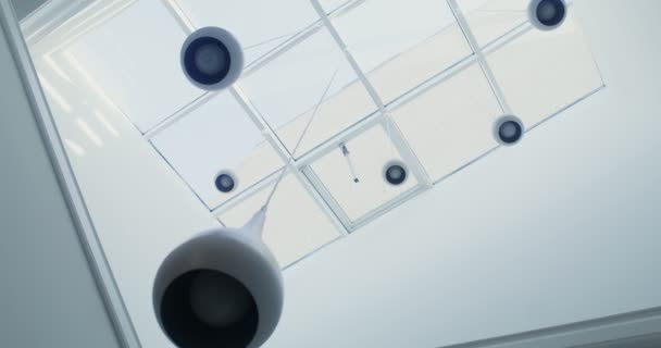 Numerosas lámparas blancas cuelgan del techo de cristal — Vídeo de stock