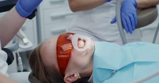 보호용 안경을 쓰고 입에 스프레더를 물고 있는 여자 환자 — 비디오