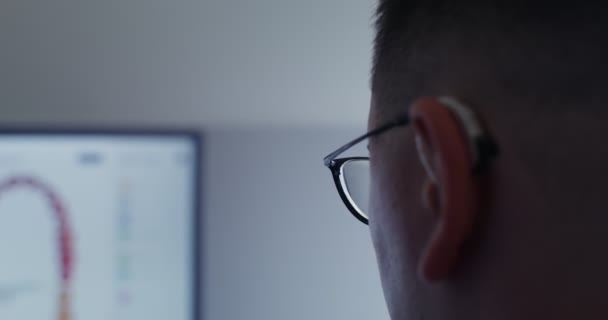 Nahaufnahme eines Teils des Kopfes eines Mannes mit Brille, der auf einen Bildschirm blickt — Stockvideo