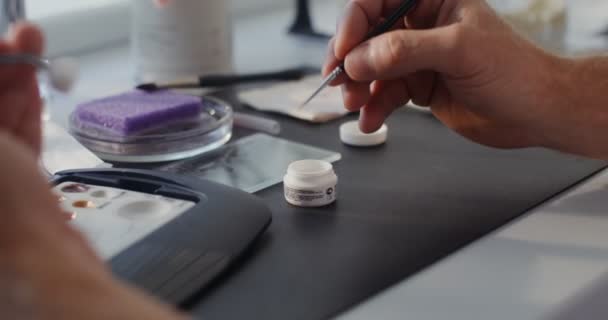 Close-up de pintar uma coroa dental cerâmica com uma escova fina à mão — Vídeo de Stock