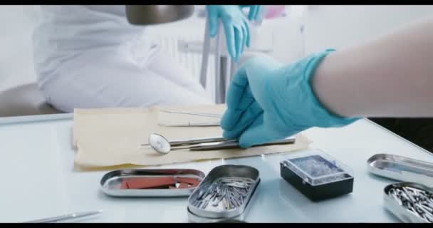 A fogorvos kezei a betegek szájüregének vizsgálatára szolgáló eszközöket vesznek. — Stock videók