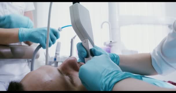 Bir hasta dişçi koltuğunda yatarken doktor dişlerini kamerayla muayene ediyor. — Stok video