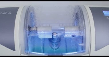 CNC diş makinesi suyla döndürerek ve parlatarak diş implantı yapıyor.