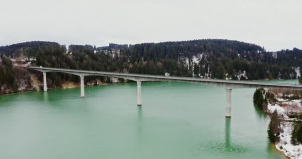 Quadcopter video z mostu przez rzekę do wzgórz pokrytych śnieżnym lasem. — Wideo stockowe