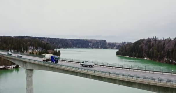 Quadcopter vídeo de uma ponte através de um rio para colinas cobertas de floresta nevada. — Vídeo de Stock