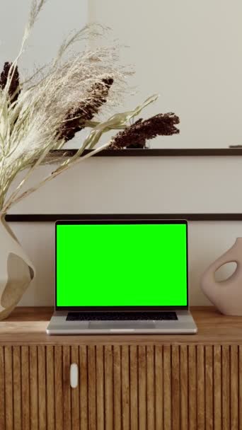 Ένα ανοικτό φορητό υπολογιστή με πράσινη οθόνη στέκεται σε ένα τραπέζι σε ένα κομψό εσωτερικό του σπιτιού — Αρχείο Βίντεο