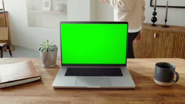 Un ordinateur portable ouvert avec un écran vert debout sur une table dans un intérieur de la maison — Video