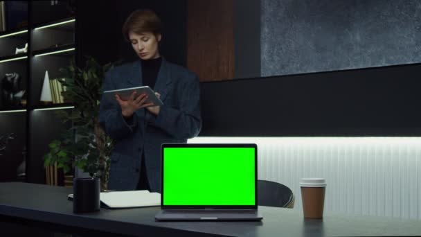 Un portátil abierto con una pantalla verde se encuentra en el escritorio de una mujer de negocios — Vídeos de Stock