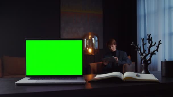 Um laptop aberto com uma tela verde fica na mesa de uma mulher de negócios — Vídeo de Stock