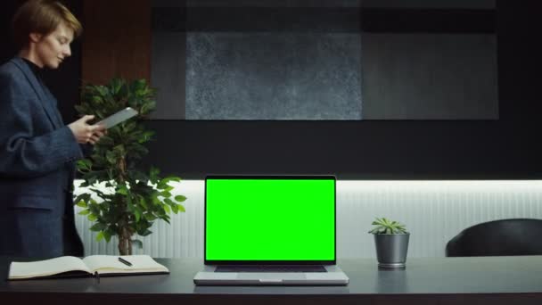 Un computer portatile aperto con schermo verde sta su un desktop in ufficio di donna d'affari — Video Stock