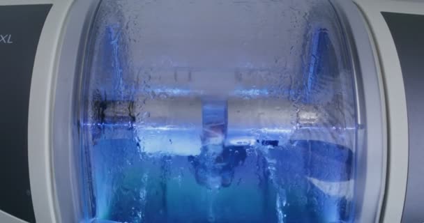 CNC dentalmaskin gör ett tandimplantat genom att rotera och polera med vatten — Stockvideo