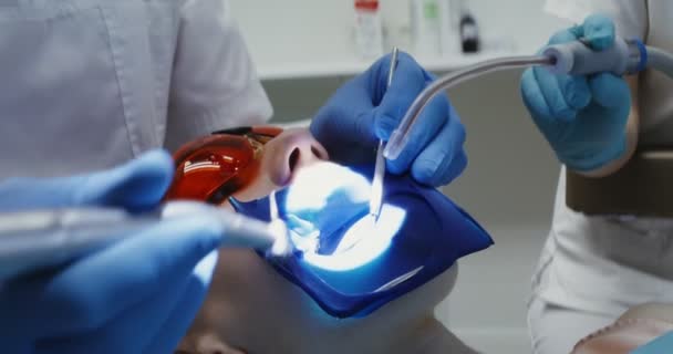 A woman patient in protective glasses with a spreader over her mouth — Stock Video