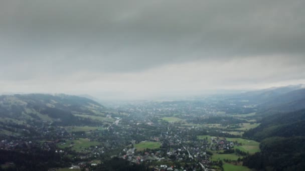 Blick auf Gebirgstal mit Stadt im Tiefland am Fuße sanft abfallender Berge — Stockvideo