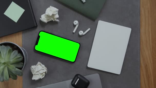 Sebuah tangan laki-laki terletak pada notebook, di sebelah ponsel dengan layar hijau — Stok Video