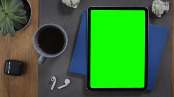 Um homem toma uma xícara de café no desktop ao lado de um tablet com uma tela verde — Vídeo de Stock