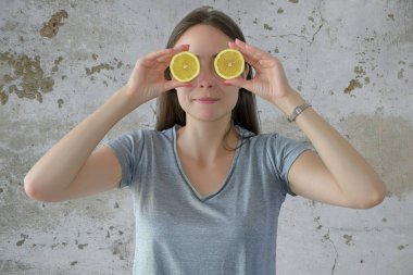 Neşeli güzel kız iki limonun yarısını tutuyor.
