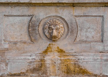 Şehirde eski taştan bir çeşme içiyor.