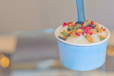 Napolili dondurma kepçeleri cam masada mavi bardakta.