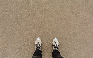 Asfalt zeminde bir çift ayakkabı, yüksek açılı ayak ya da çiçek.