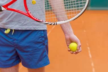 Tenisçi sahada raket ve sarı top tutuyor.