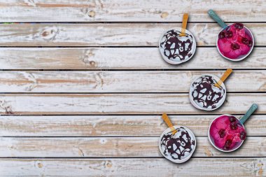 Beyaz paslı ahşap masaya izole edilmiş bardaktaki birkaç dondurma çeşidi.