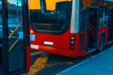 Otobüsteki iki kırmızı otobüs günün akşamında şehir sokağında durur.