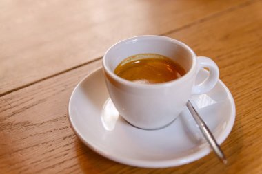 Beyaz fincanlı kahve, üzerinde espresso olan bir kafeterya, ahşap masa.