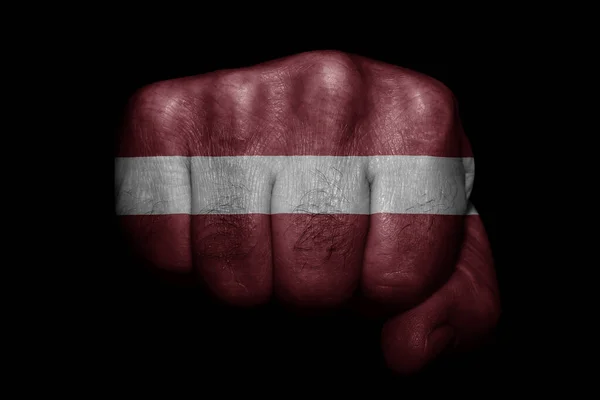 拉托维亚国旗在黑色背景上的有力拳头上 — 图库照片