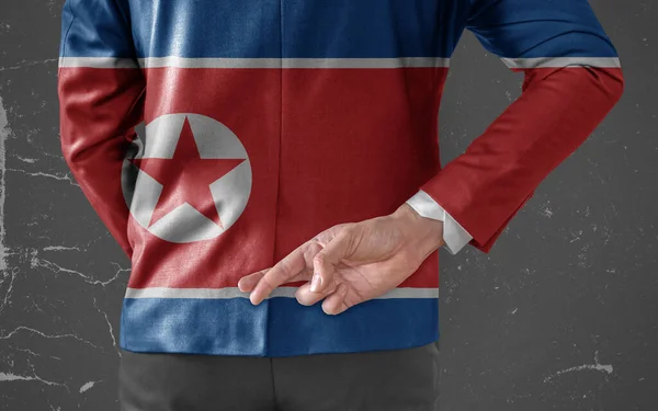 北朝鮮の旗を背負ったビジネスマンジャケット彼の指で彼の背中の後ろに交差 — ストック写真
