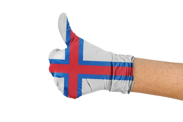 法罗群岛的国旗挂在印有大拇指标志的医疗手套上 — 图库照片