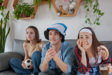 Üç genç Arjantinli arkadaş, iki kız ve bir oğlan futbol seyrediyor, hayal kırıklığına uğramış ve çaresiz..