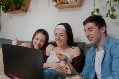 Üç genç arkadaş, bir erkek ve iki kız, dizüstü bilgisayarda çizgi film izliyorlar..