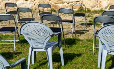 Çeşitli modellerin sandalyeleri çimenli bir alanda tek bir yere yerleştirildi.