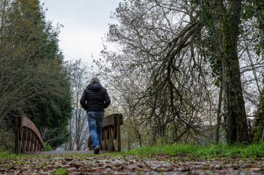 Adam sonbaharda kuru yapraklarla dolu bir yolda yürüyor.